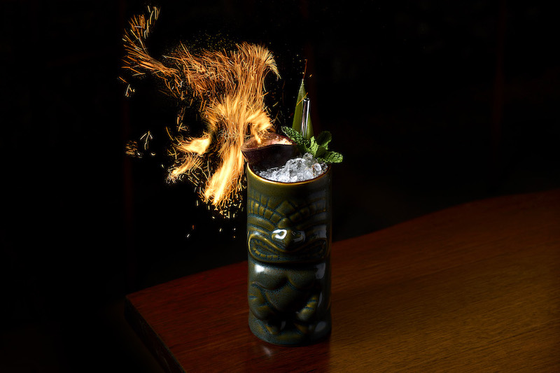 The naught zombie cocktail with flames coming out the top